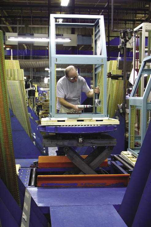 An assembly technician attaches a side brace on painted enclosure frame.