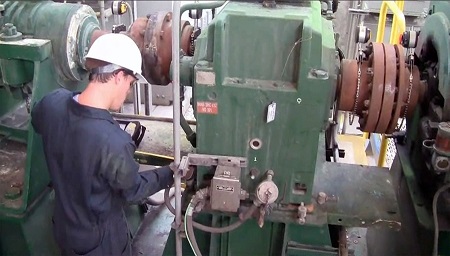 The technician works to align an industrial drive train, an arrangement similar to that found in wind turbines.