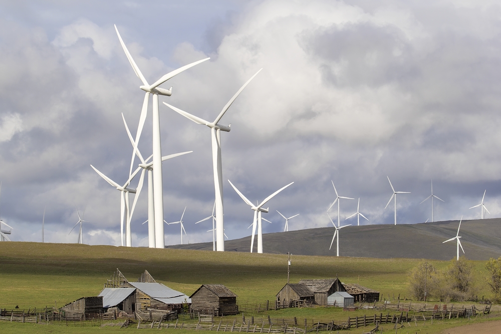 Wind turbines in wind farm towering over cattle ranch buildings on Rollings Hills along Columbia river in Washington state.