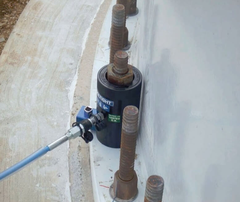 A bolt tensioner pulls the bolt while another tool (just visible above the hydraulic hose) gently tightens the nut.